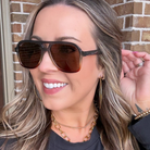 Woman wearing sunglasses with a brick wall background