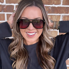 Woman wearing sunglasses with a brick wall background