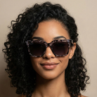 Woman wearing leopard print sunglasses against a beige background