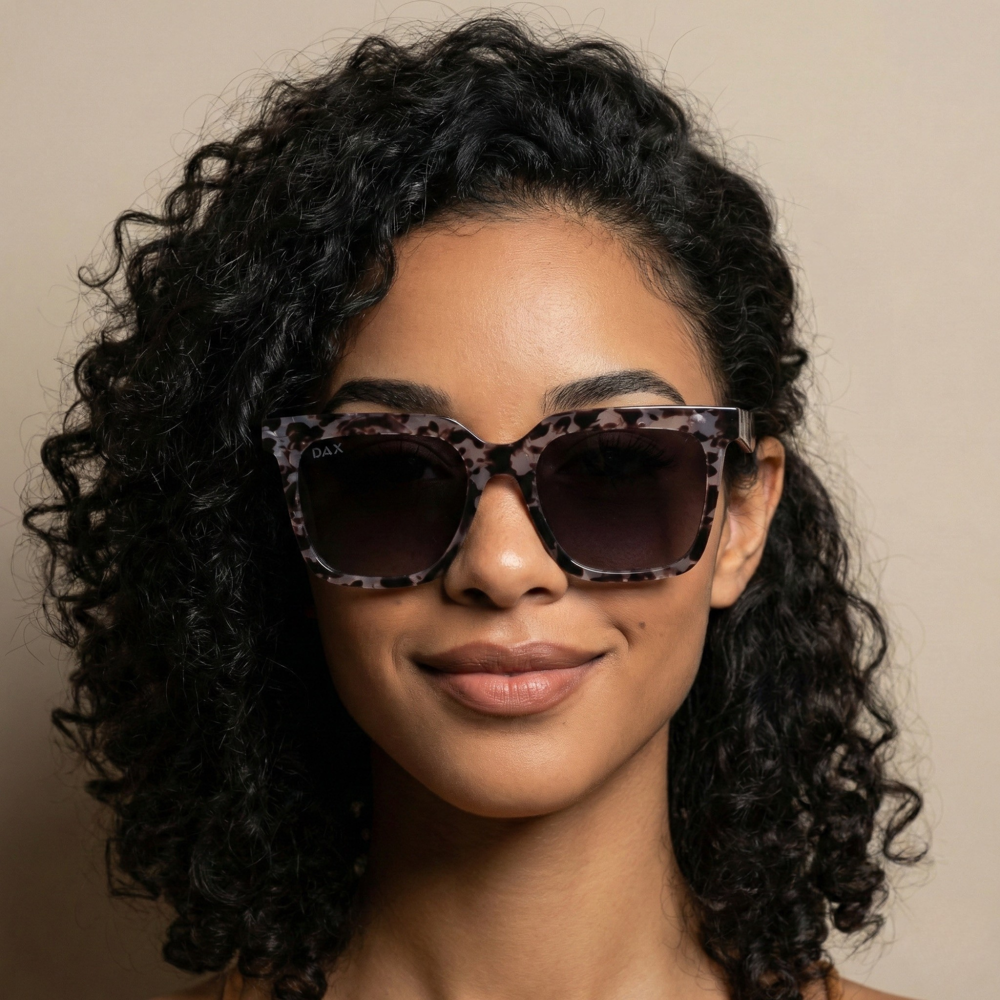 Woman wearing leopard print sunglasses against a beige background