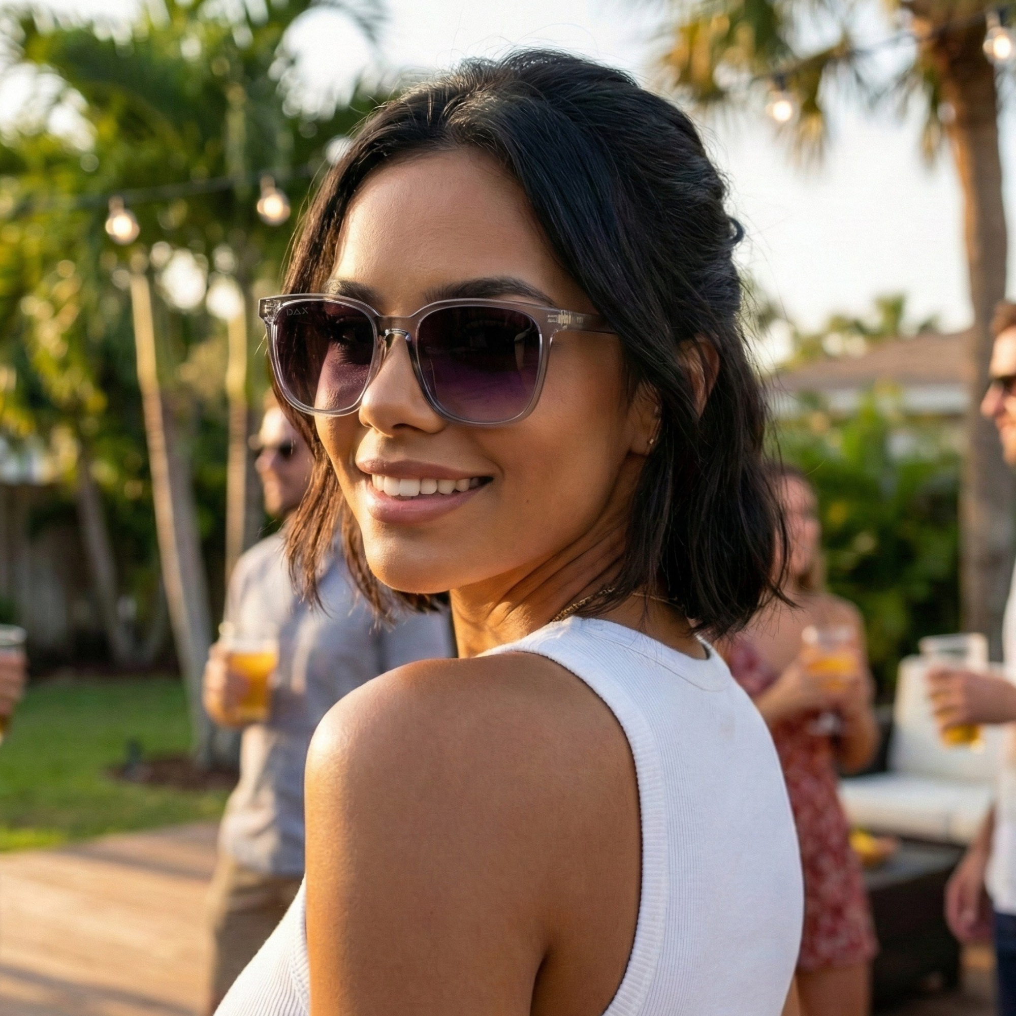Woman wearing sunglasses at a social gathering with blurred background