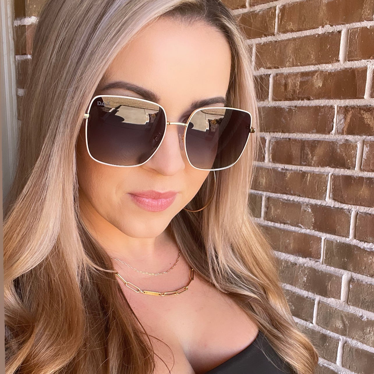 Woman wearing sunglasses with a brick wall background