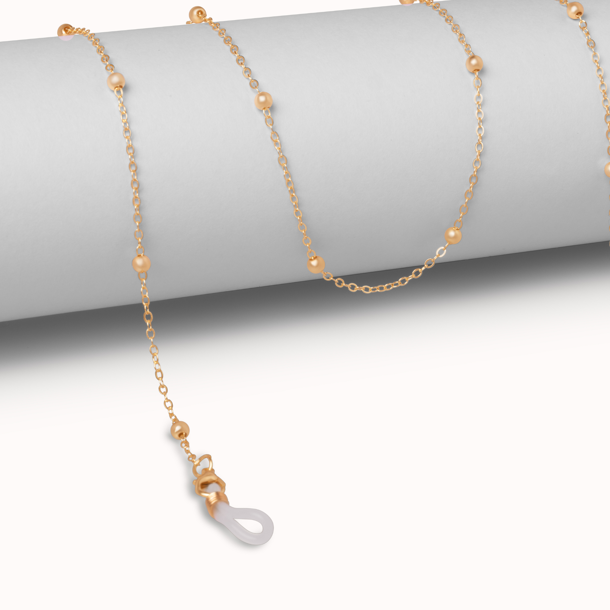 A delicate gold chain necklace with small gold beads and a white teardrop-shaped stone pendant, draped over a light gray cylindrical display stand.