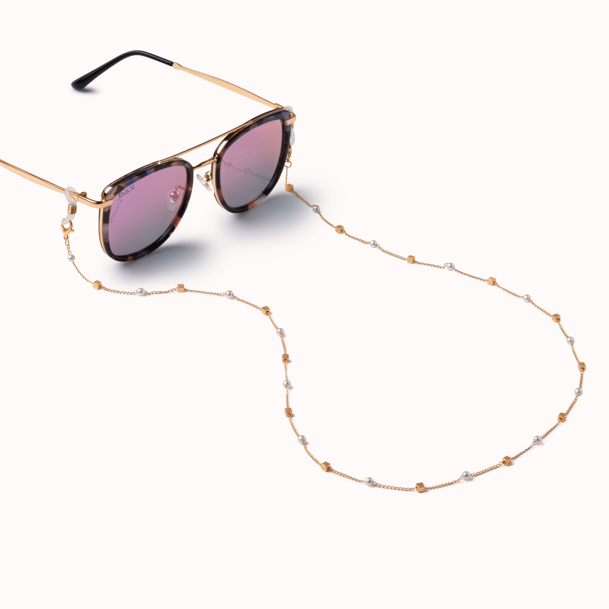 Gold-framed sunglasses with tortoiseshell-patterned dark lenses and a matching gold chain strap with small clear rhinestone accents, displayed on a clean off-white background.
