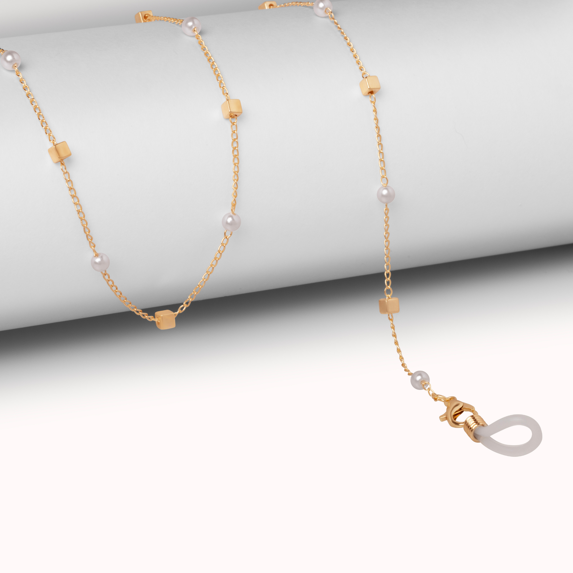 Gold necklace with pearl beads on a light gray background