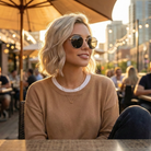 Woman wearing sunglasses sitting outdoors with a cityscape background