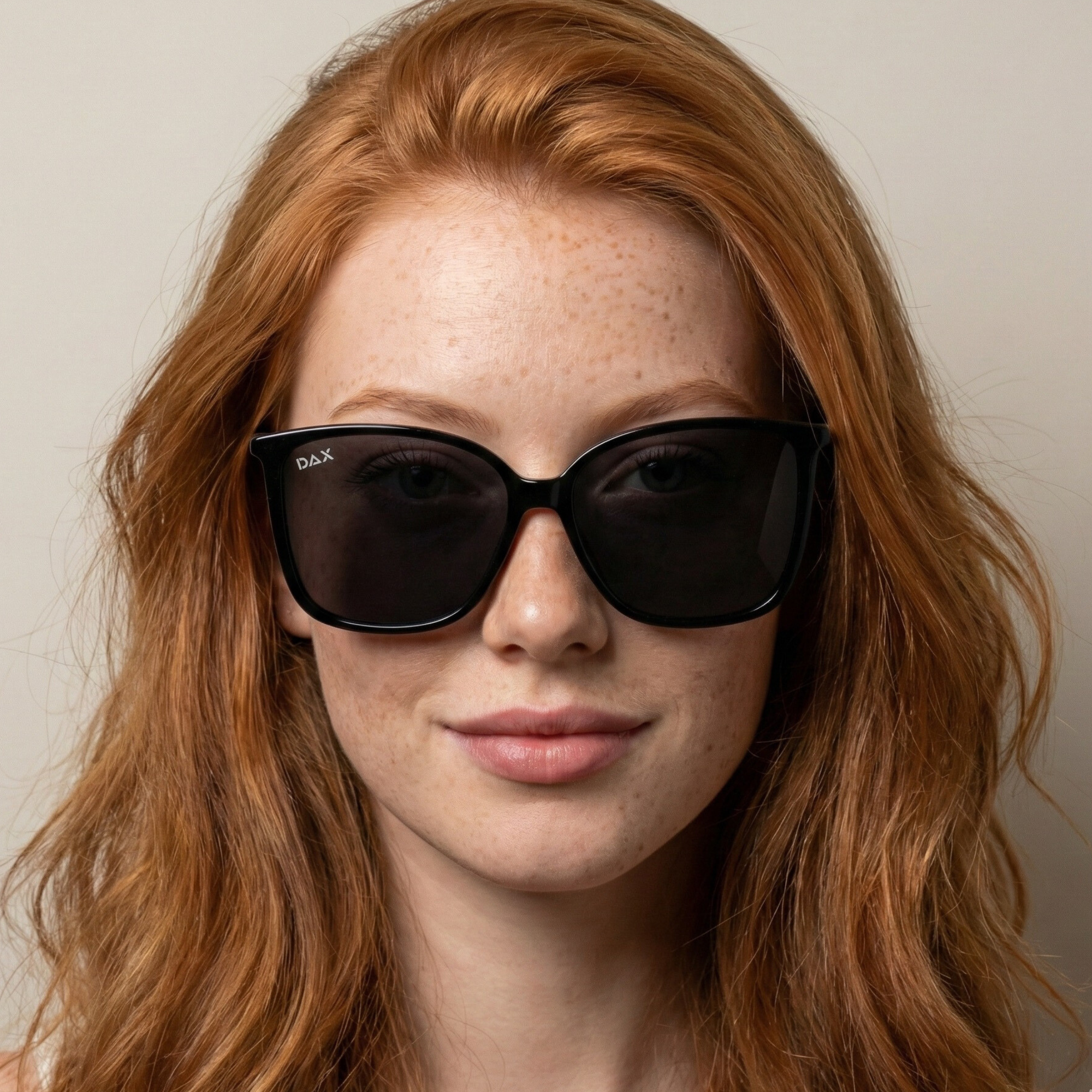 Woman wearing large black sunglasses with a neutral background