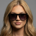 Woman wearing dark sunglasses with a neutral background