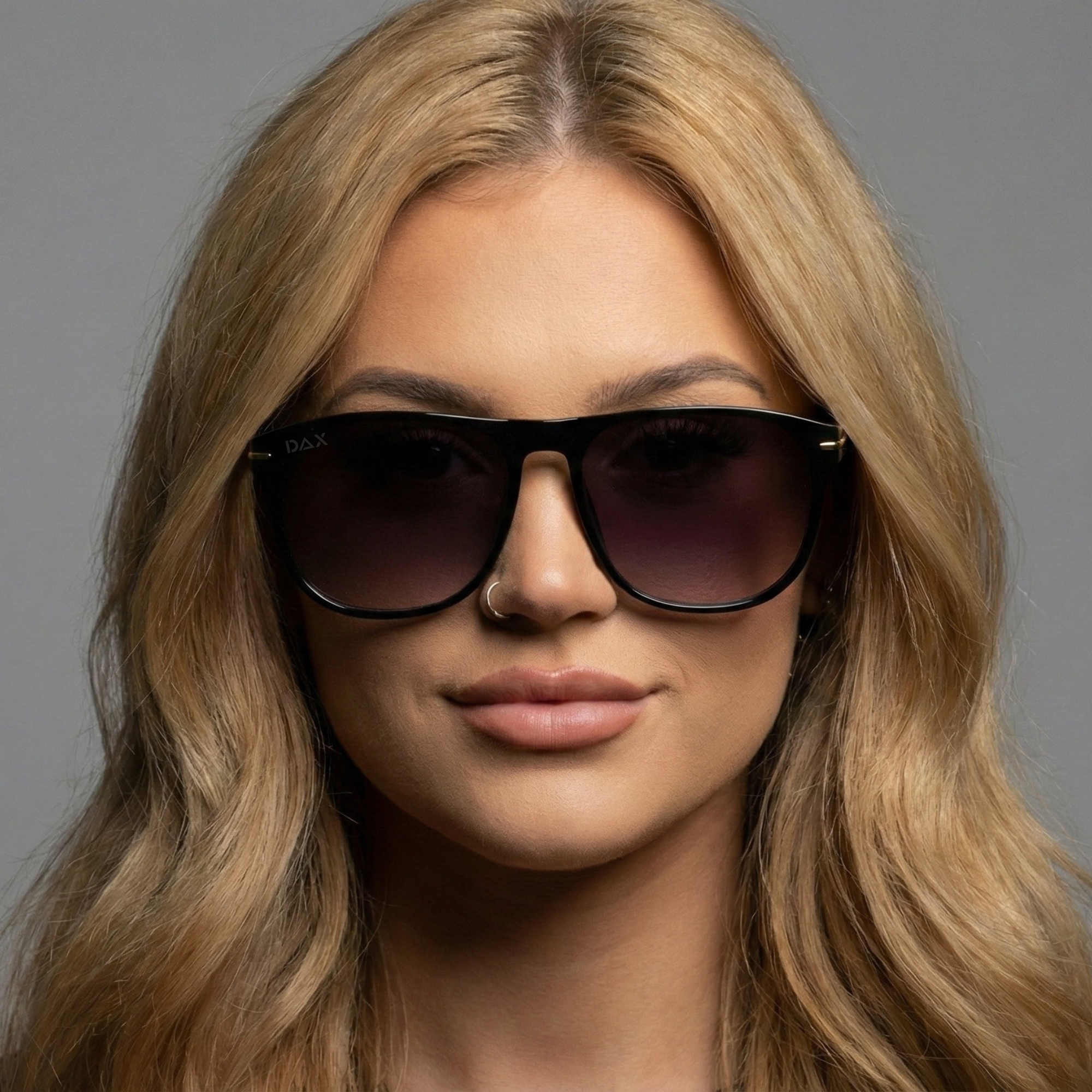 Woman wearing dark sunglasses with a neutral background