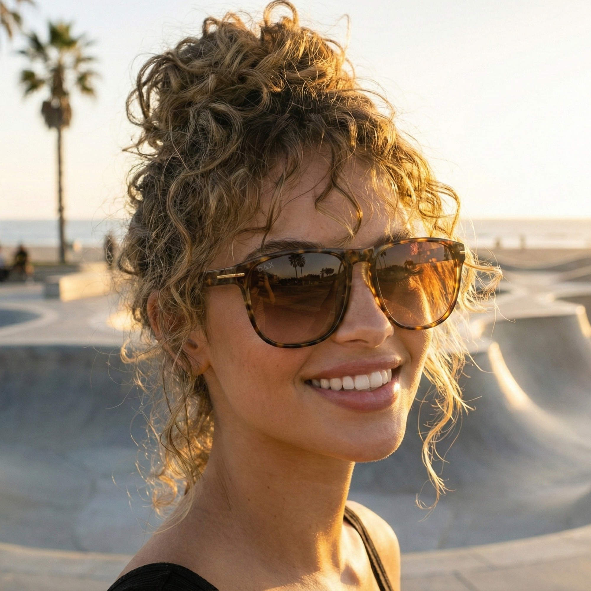 Woman wearing sunglasses with a skate park and palm trees in the background