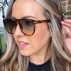 Woman wearing tortoiseshell sunglasses with a blurred outdoor background