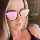 Woman wearing colorful cat-eye sunglasses with a brick wall background