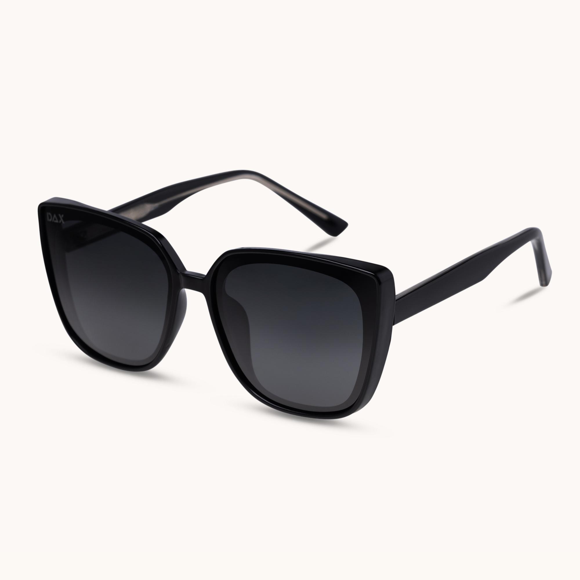 Black cat-eye sunglasses with dark gradient lenses, shown at an angle on a light cream background.