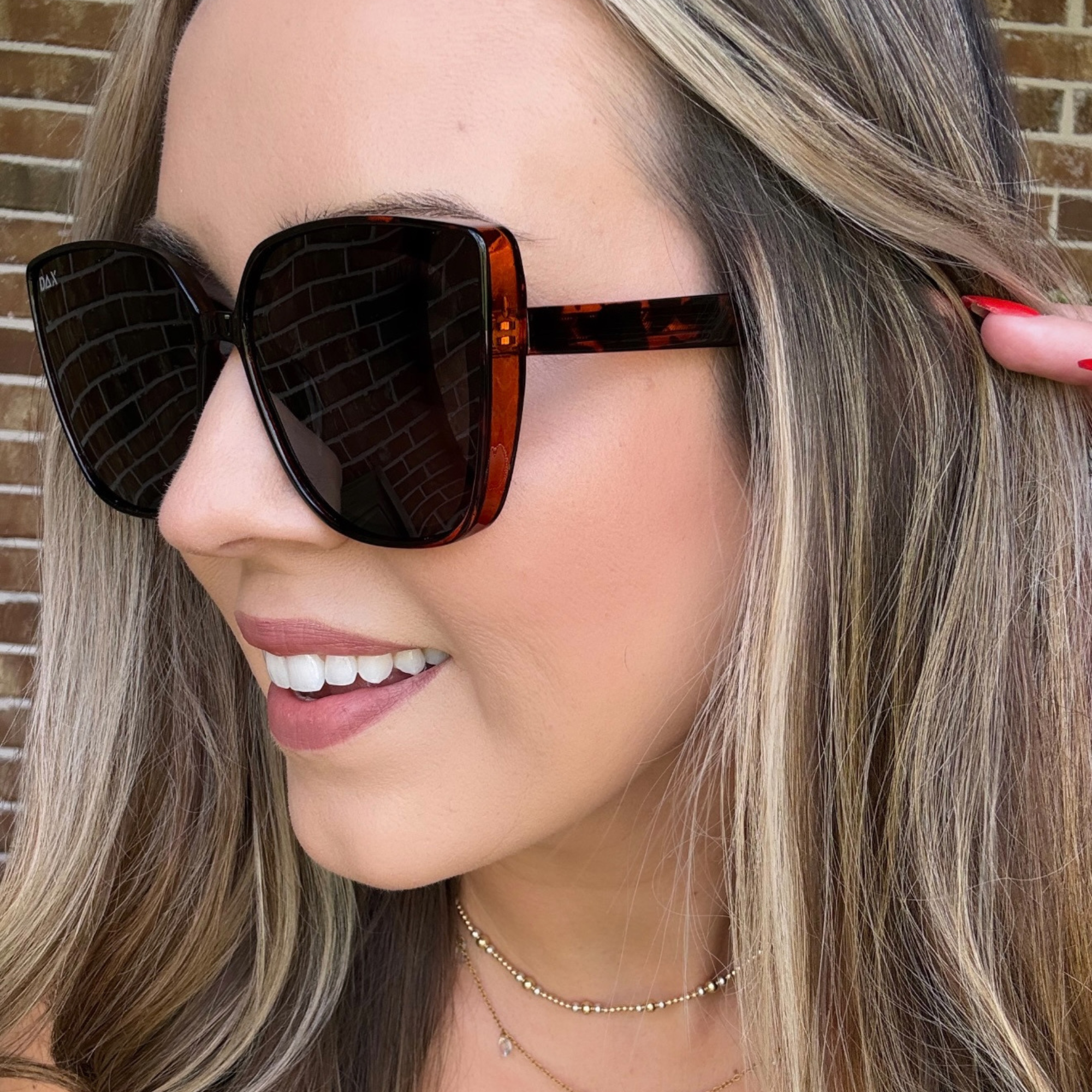 Woman wearing tortoiseshell sunglasses with a blurred background