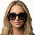 Woman wearing Lyla black sunglasses with a plain background