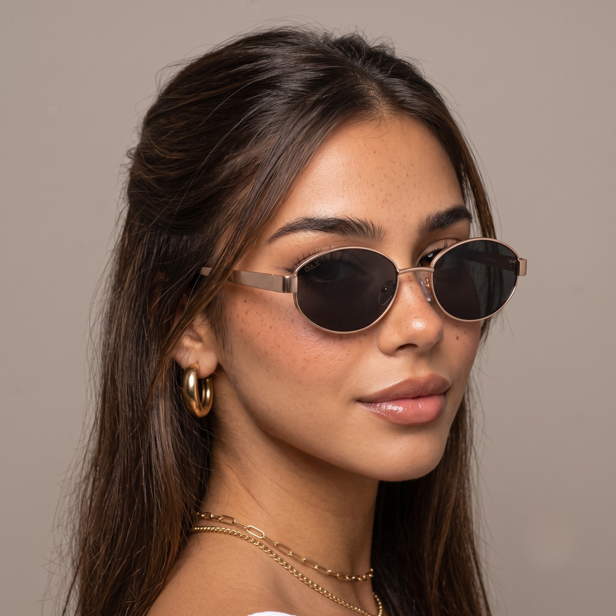 Brunette woman wearing gold rimmed oval sunglasses.