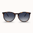 Round sunglasses with a dark brown and black tortoiseshell frame and gradient gray lenses, shown against a light cream background.
