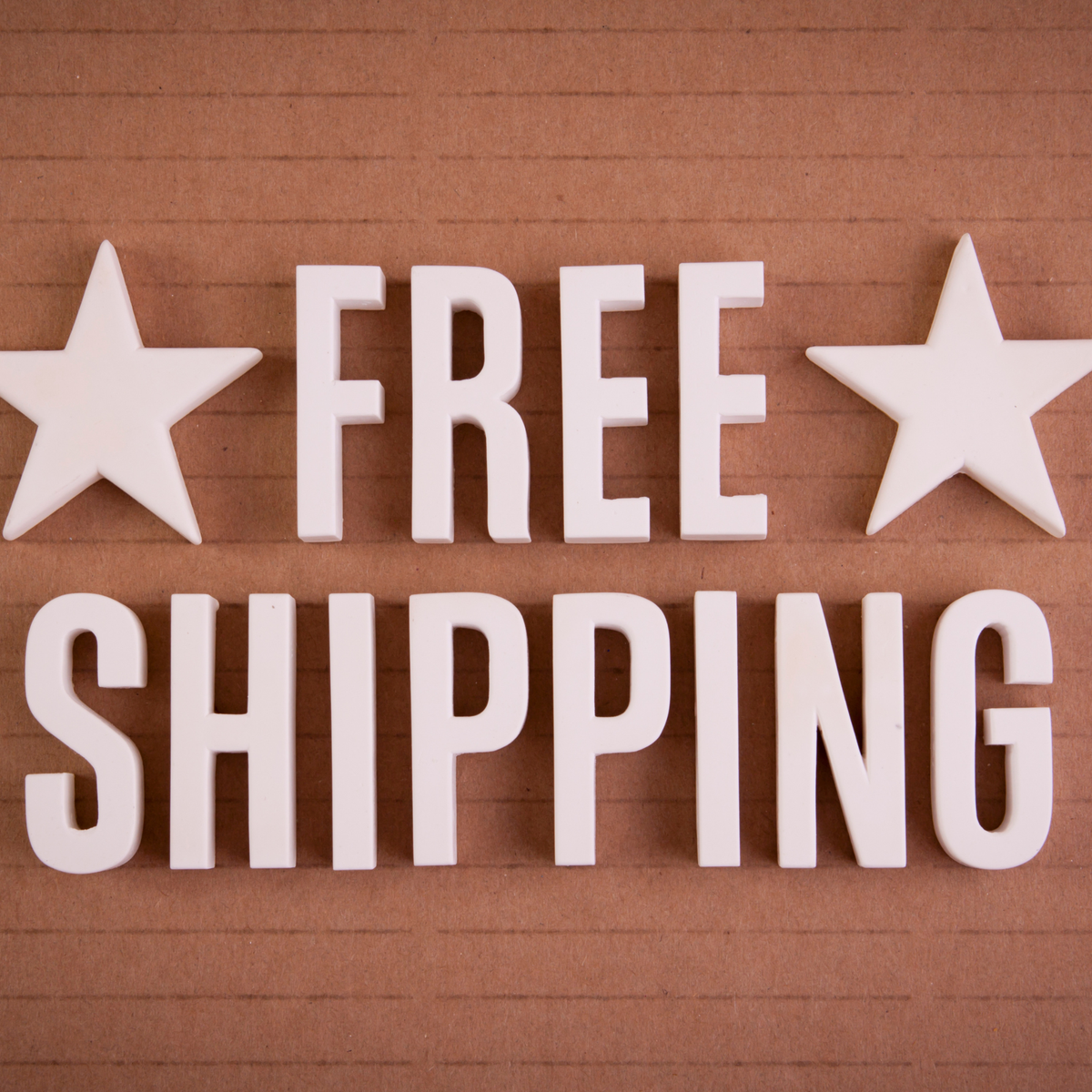 White 3D block letters spelling 'FREE SHIPPING' with two white stars on either side, set against a brown corrugated cardboard background.