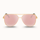 Gold-framed sunglasses with pink lenses on a white background