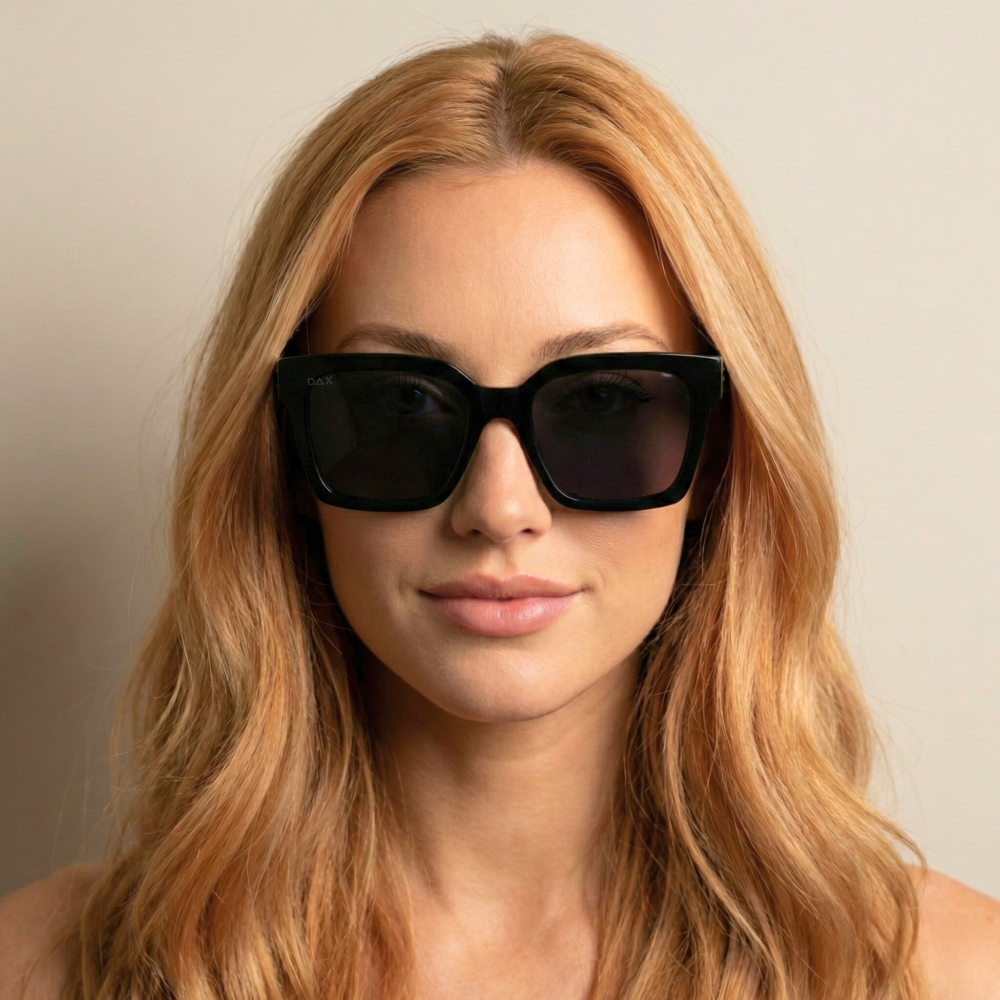 Woman wearing black horned sunglasses with a neutral background