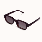A pair of square-frame sunglasses with a translucent dark burgundy acetate frame and dark gray gradient lenses, shown on a clean off-white background.